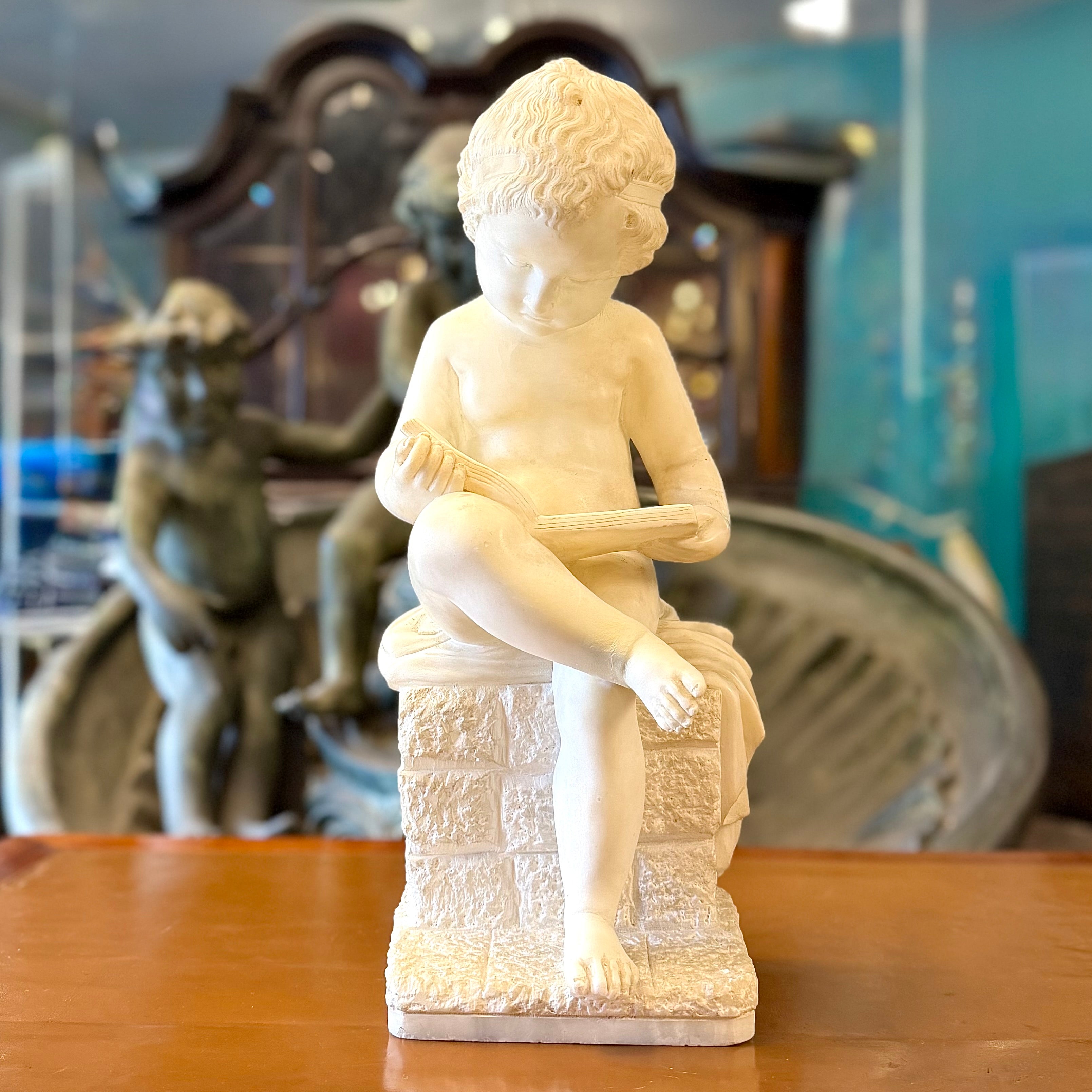 Escultura de alabastro de un "putti" niño leyendo tranquilamente. Italia SXIX