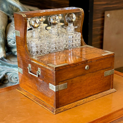 Tantalus de roble de tres botellas con compartimento secreto y caja de juegos. Londres XIX